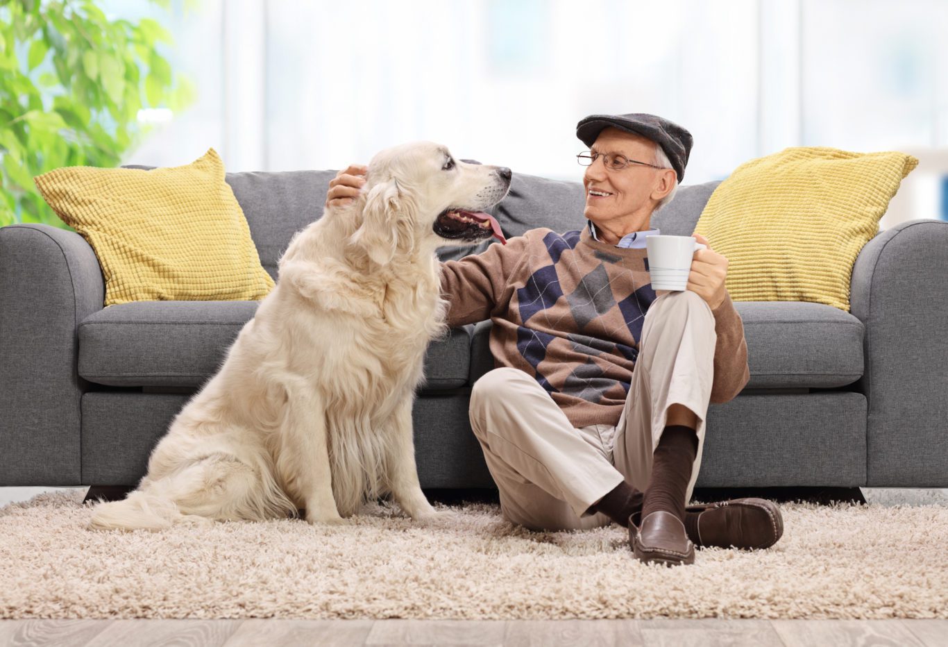 A senior man sitting on the floor and petting his dog
