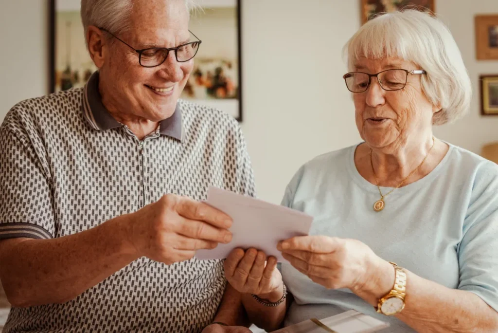 Older man and woman smiling as they look at a photograph together