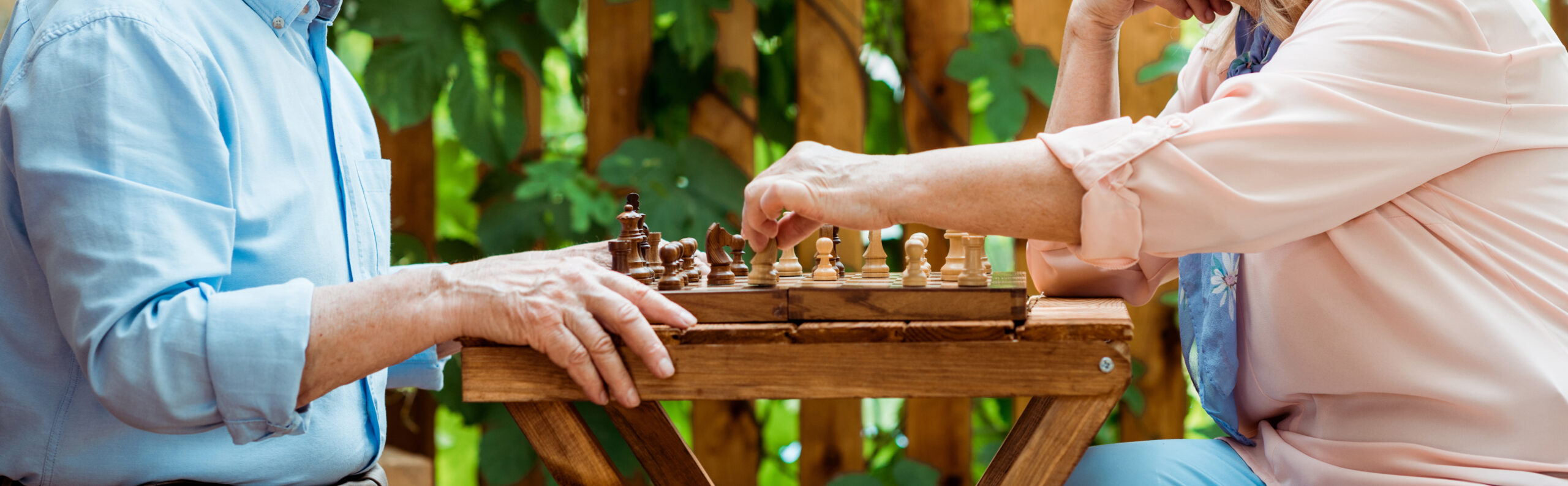 A retired couple playing chess on wooden table