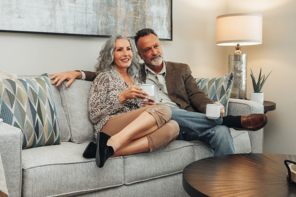 Post-Retirement man and women enjoying a cup of coffee on the couch at true connection communities