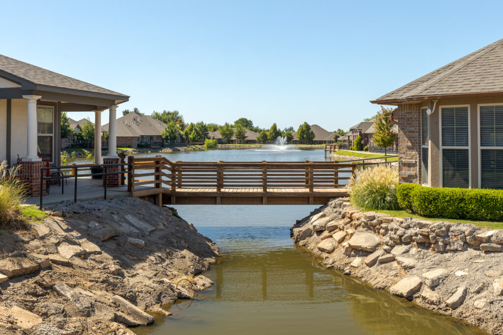 A walking bridge hangs over a stunning lake at Grace Pointe Senior Living Community in Oklahoma.