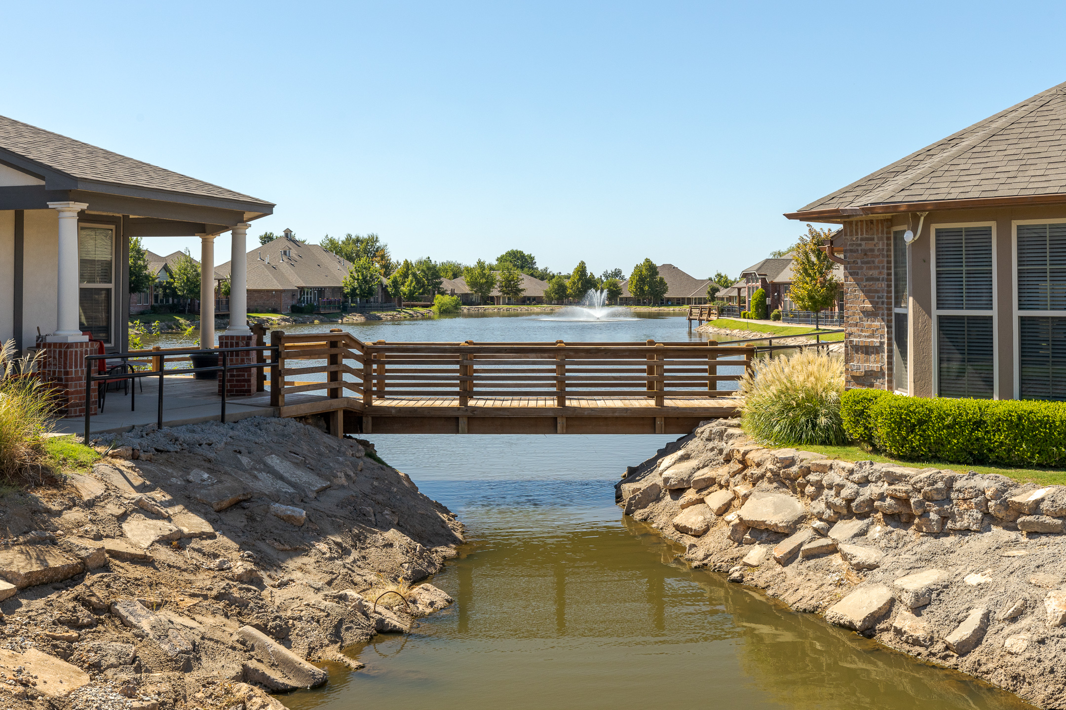 A walking bridge hangs over a stunning lake at Grace Pointe Senior Living Community in Oklahoma.