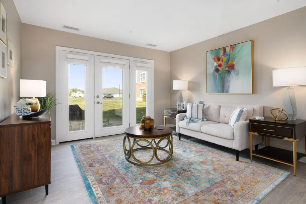 Living room with a cream sofa, a patterned rug, a round coffee table and French doors