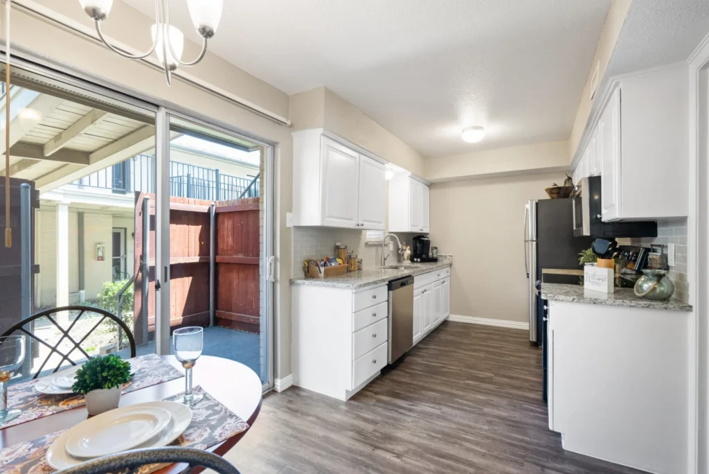 Apartment kitchen with white cabinets and a small dining table beside sliding glass doors