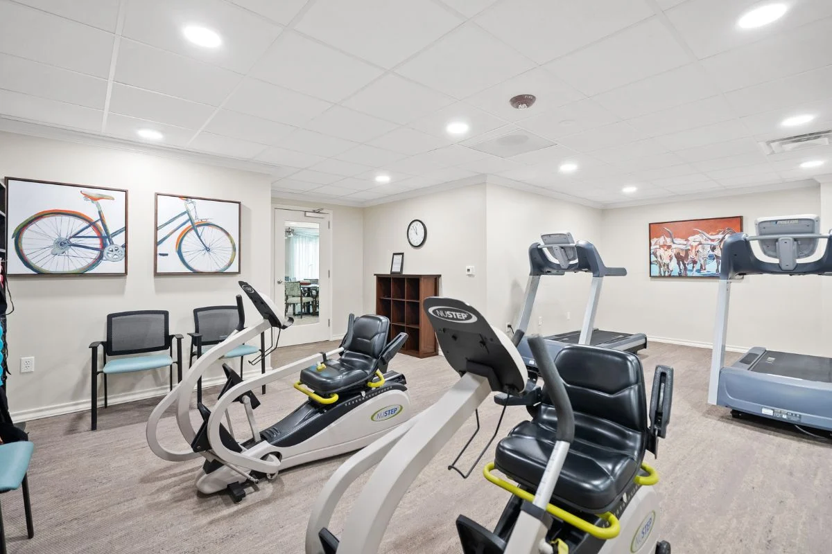 Fitness room with exercise bikes and treadmills, with framed bicycle art on the walls