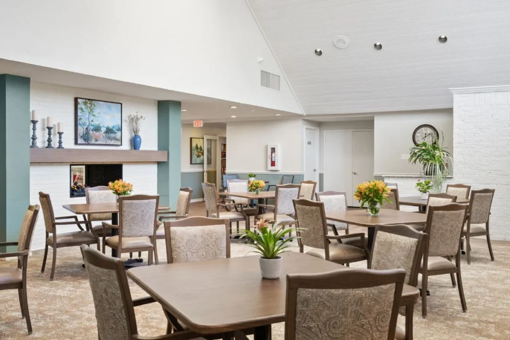 Dining and lounge area with tables and chairs, a fireplace and a high ceiling with large windows