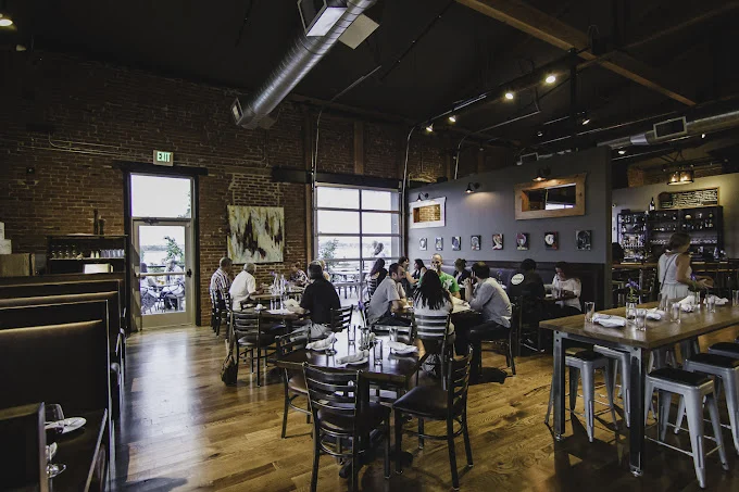 Restaurant interior with brick walls, tables with diners and large windows