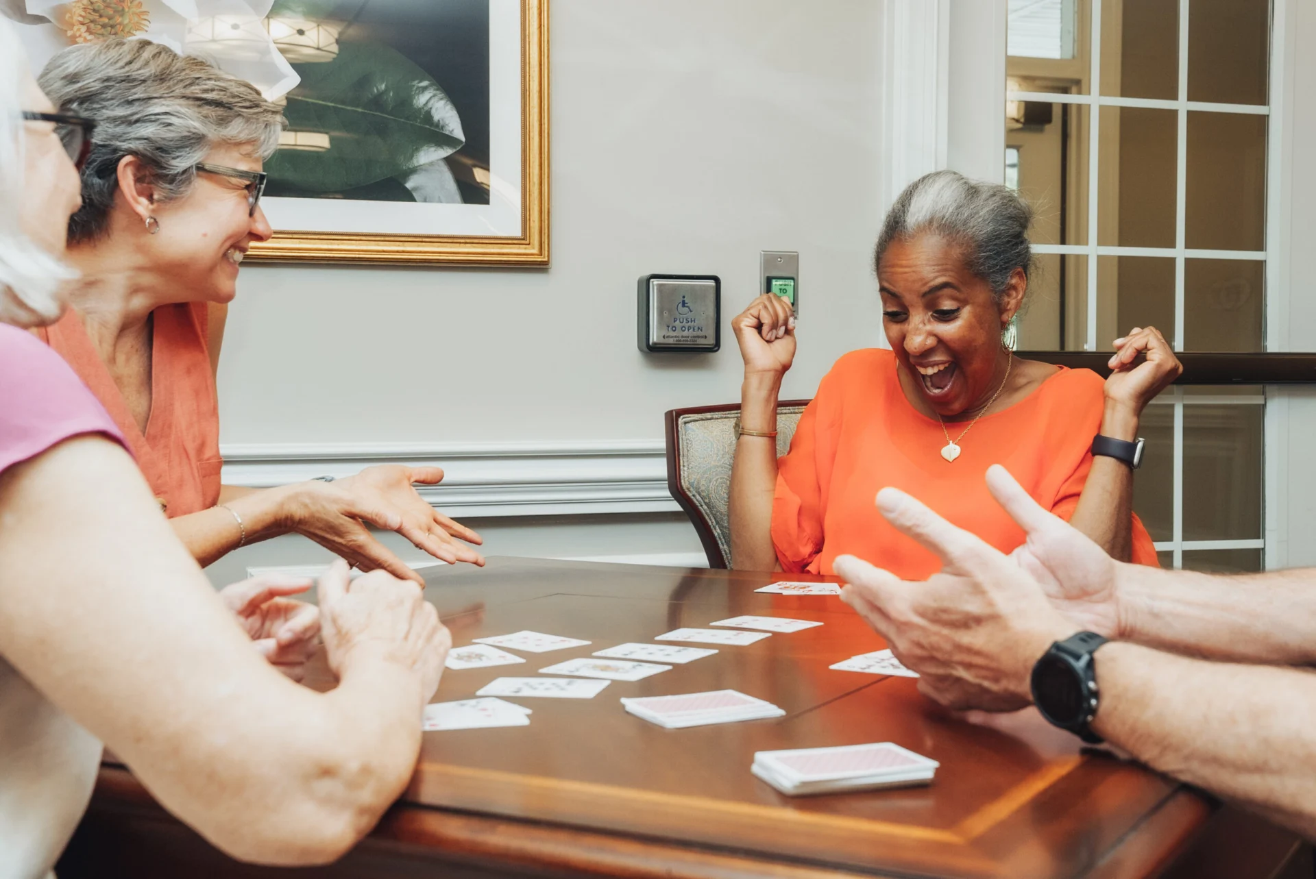 Older adults laughing while playing cards around a table