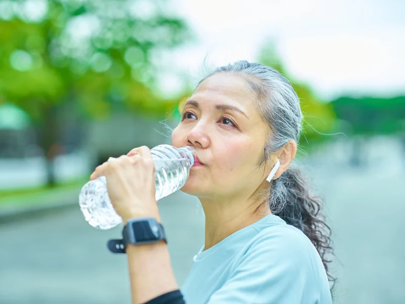 Woman drinking from a water bottle outdoors after exercising