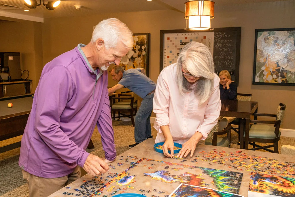 Older man and woman working together on a large jigsaw puzzle