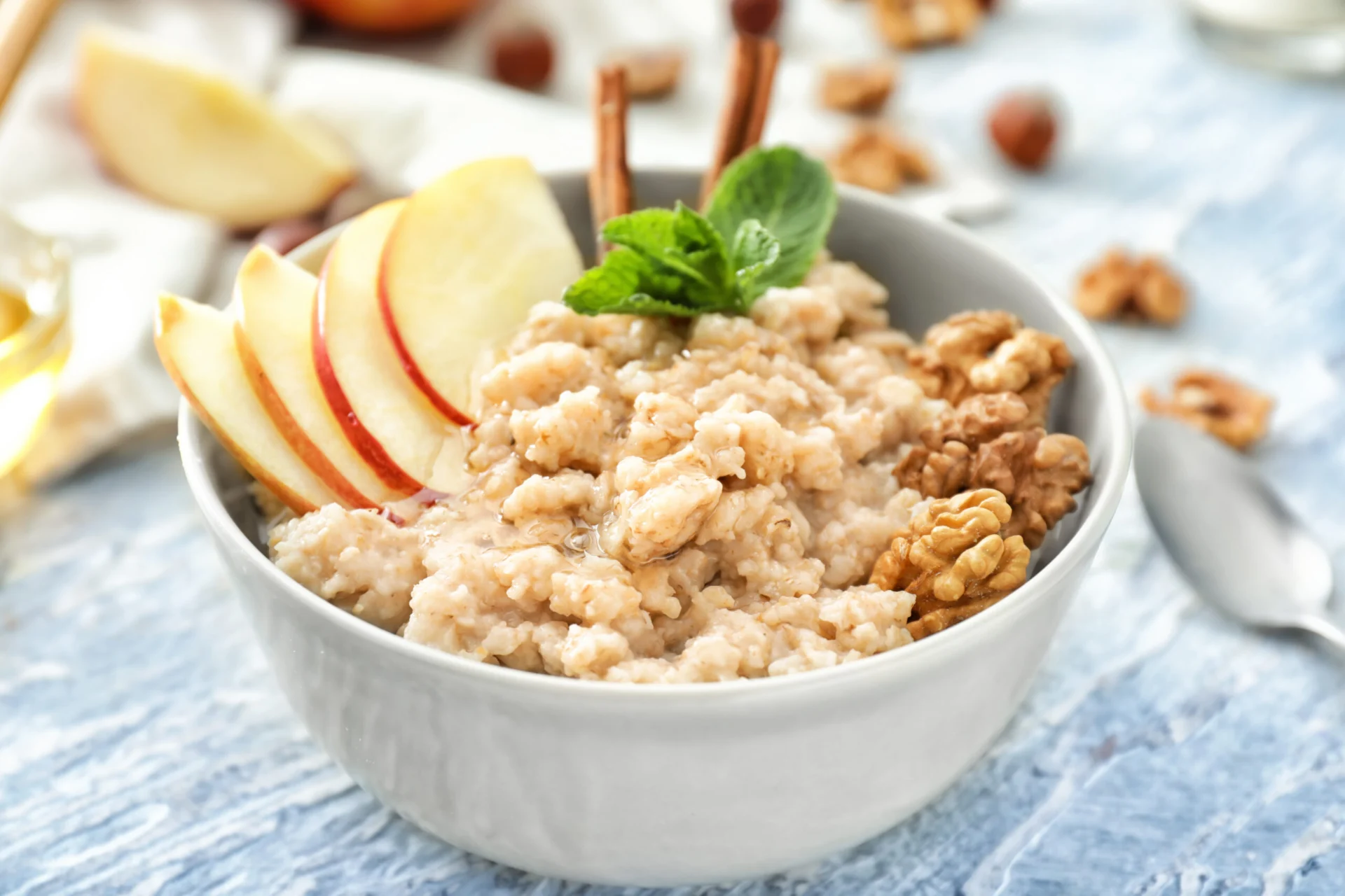 Tasty oatmeal with apple and walnut in bowl on table