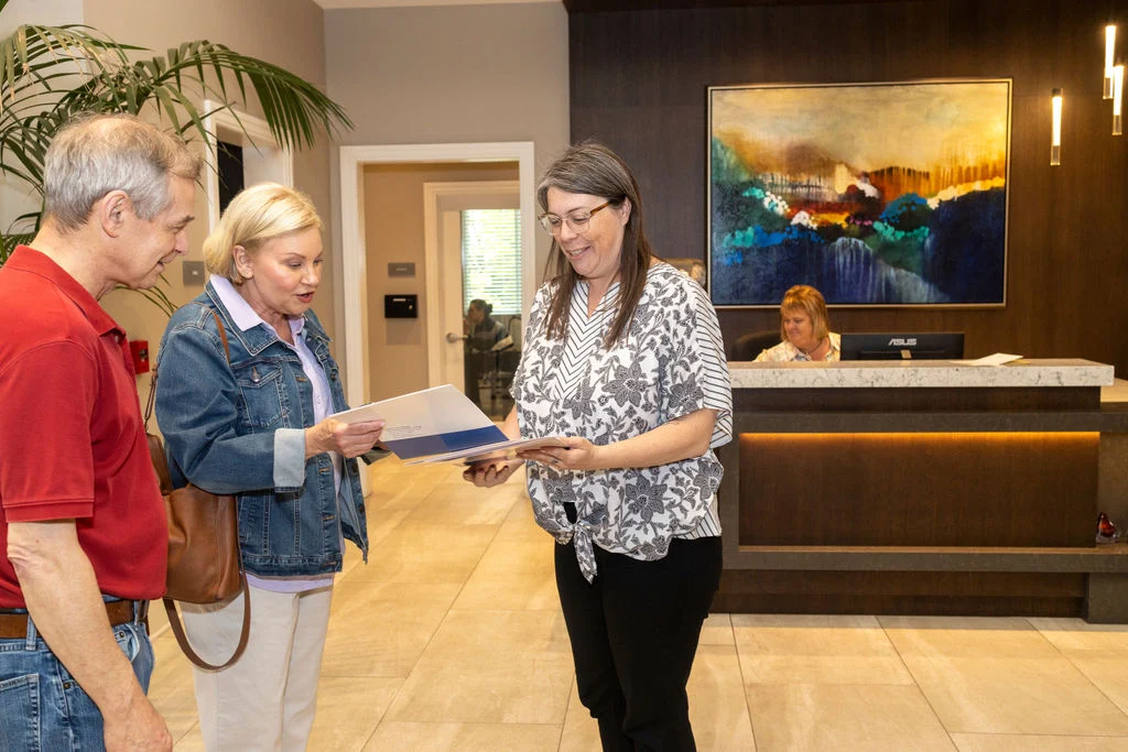 Woman holding a folder speaking with a couple in a lobby