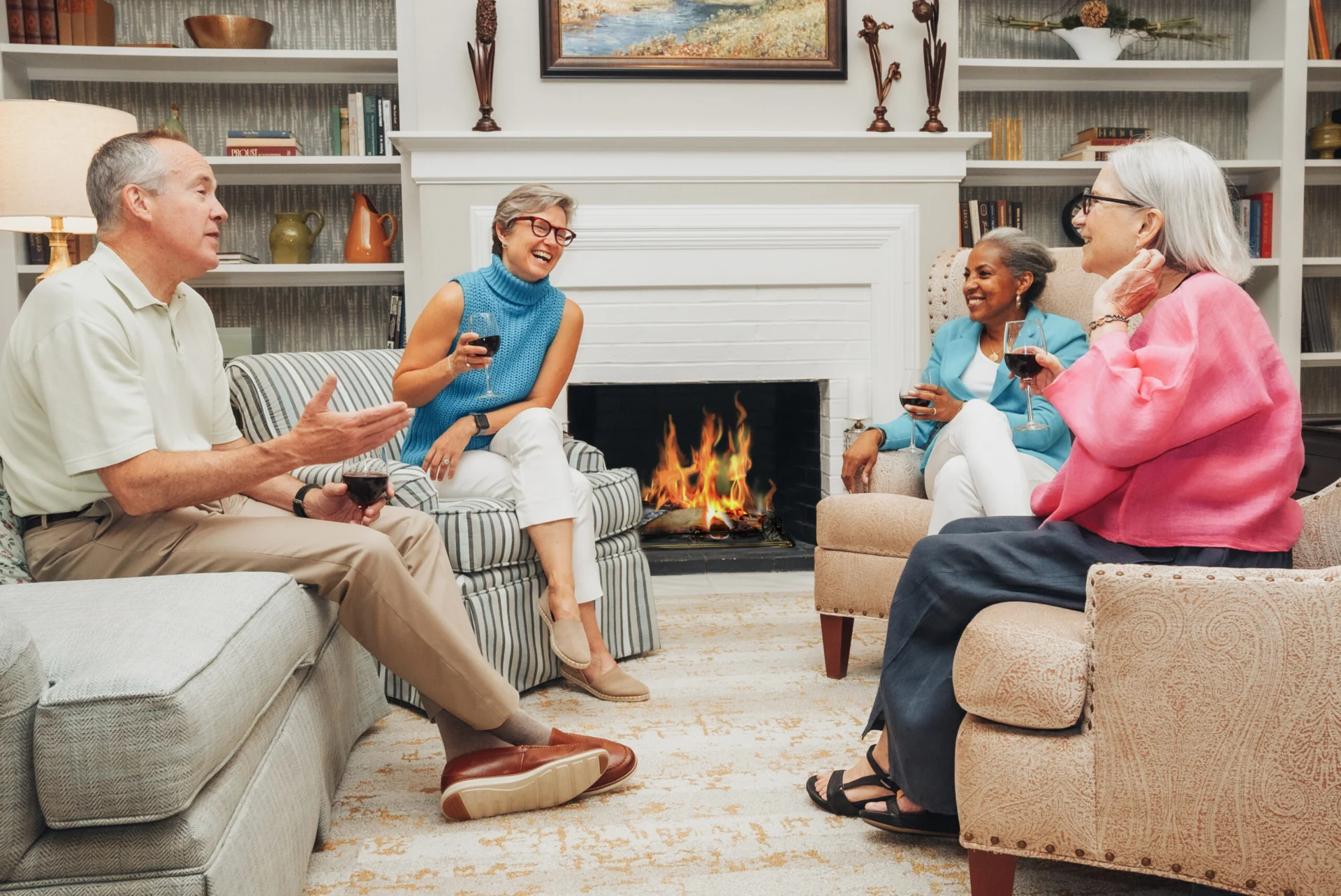 Older adults chatting in armchairs around a fireplace in a living room