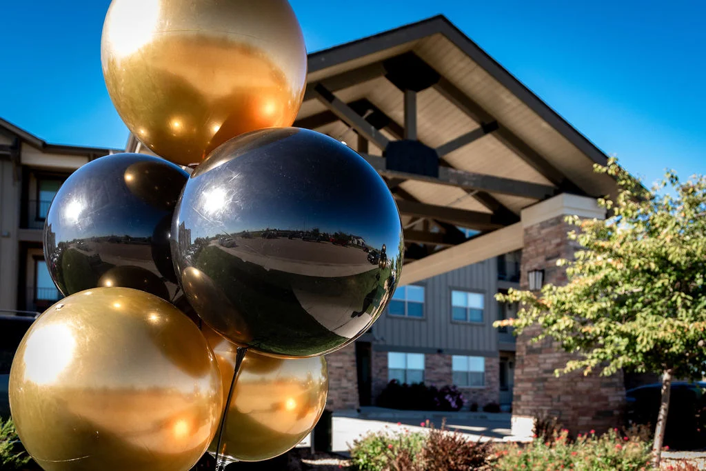 Gold and black balloons in front of a building entrance with a timber roof