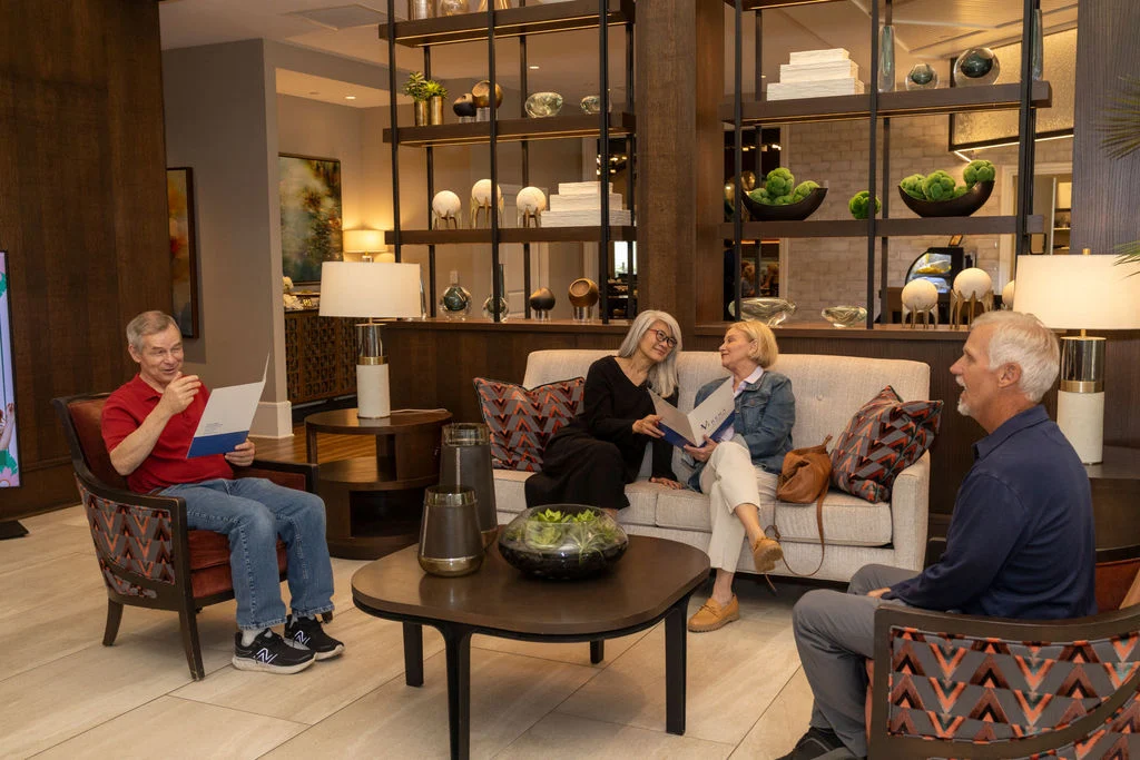 Older adults relaxing and reading in a lounge with built-in shelving and armchairs