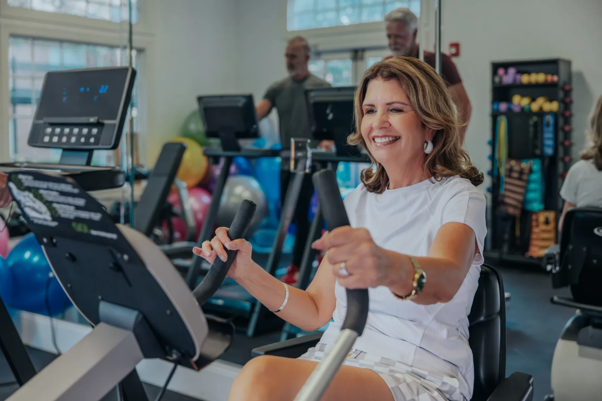 Smiling woman riding a stationary exercise bike in a fitness center