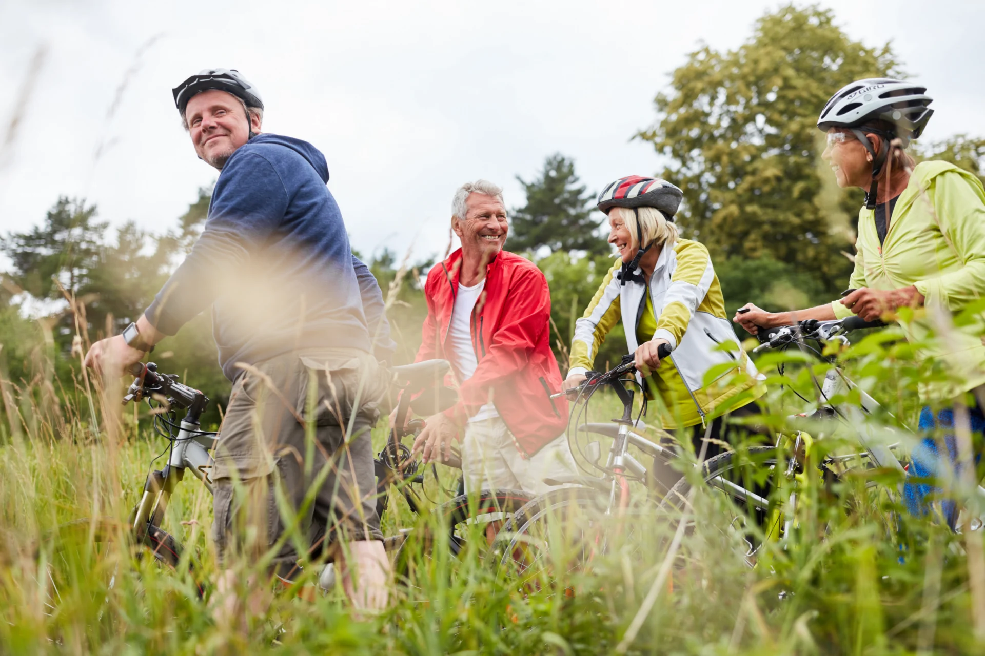 Group of cyclists in helmets riding through tall grass