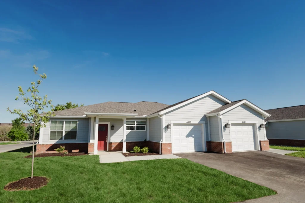 Single-story home with a two-car garage and lawn under a clear blue sky