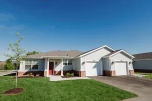 Single-story home with a two-car garage and lawn under a clear blue sky