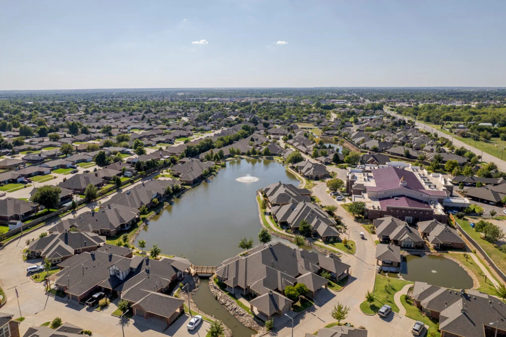 Aerial view of a neighborhood of single-story homes around a pond