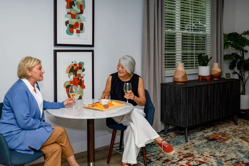 Two women seated at a small round table sharing snacks and conversation
