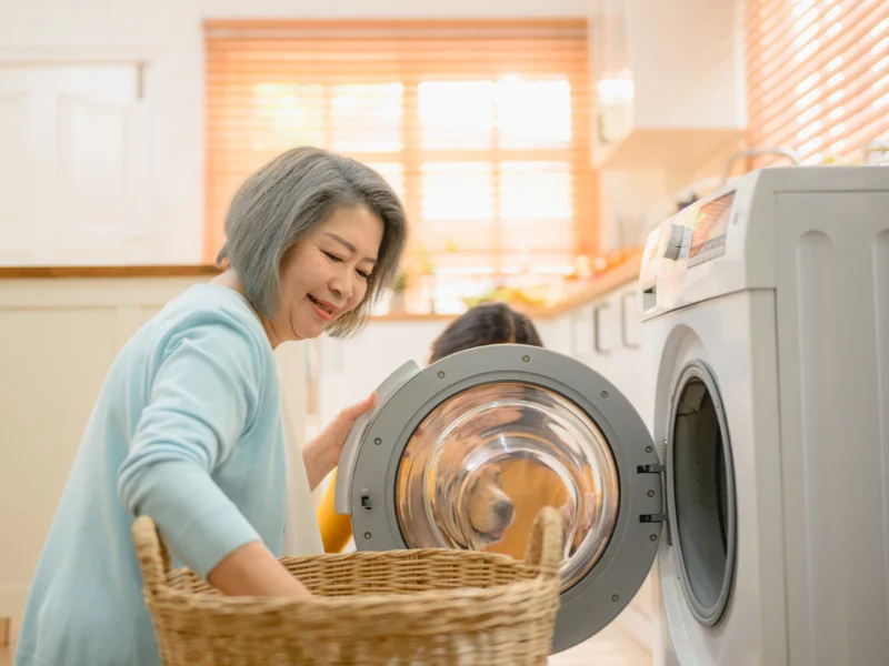 Woman smiling as she loads laundry into a front-loading washing machine