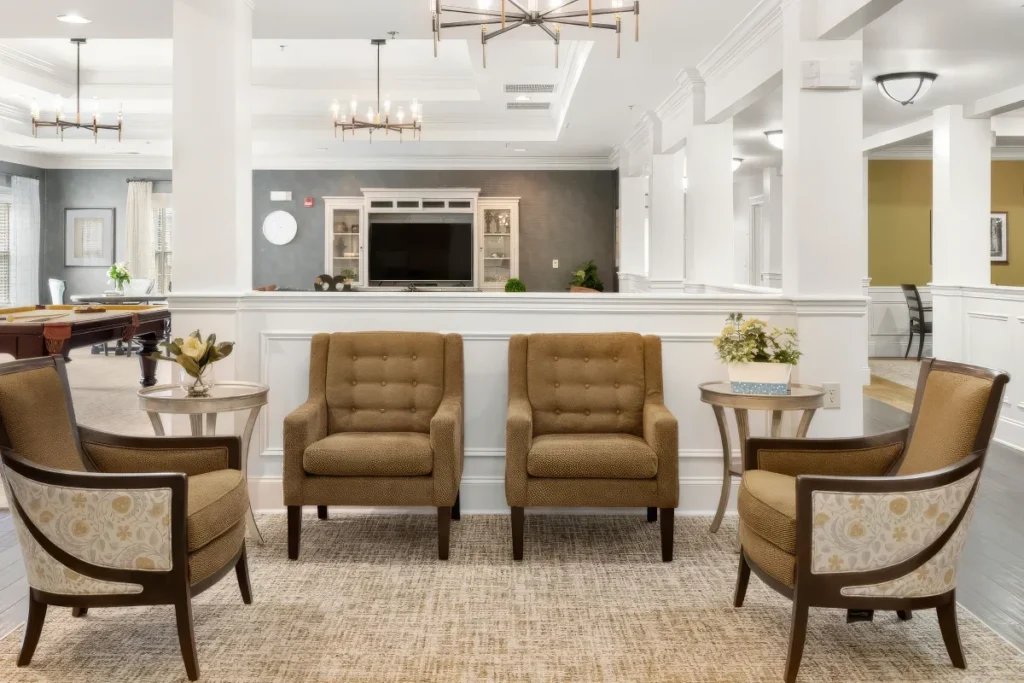 Lobby lounge with tan armchairs, small tables and a reception counter with a TV behind