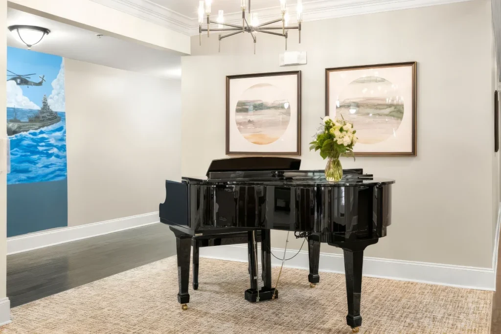 Grand piano with framed art and a vase of flowers in a lounge