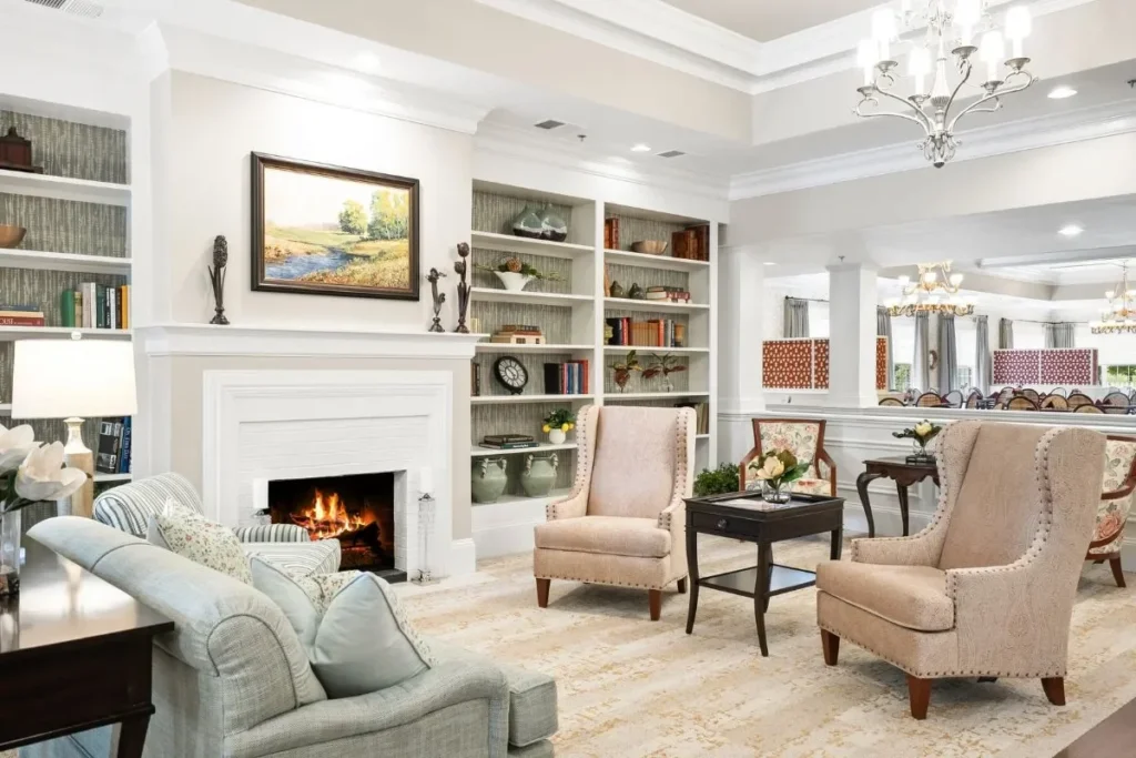 Living room with a fireplace, armchairs, a sofa and built-in bookshelves under a tray ceiling