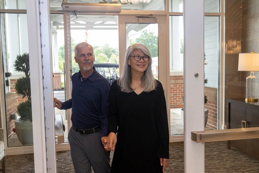 Smiling older couple standing in a building entryway, holding hands