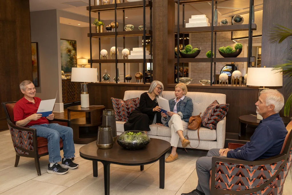 Older adults relaxing and reading in a lounge with armchairs, a sofa and a coffee table