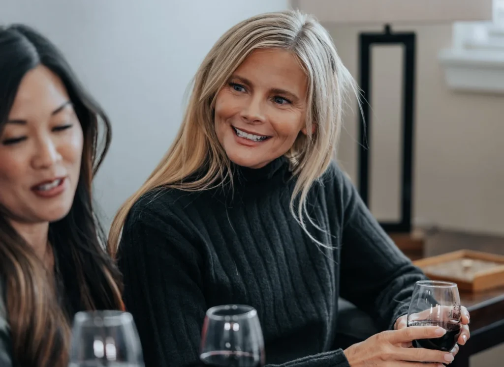 Two women smiling and chatting over glasses of wine
