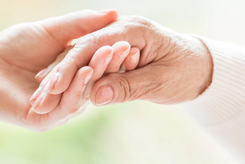 Close-up of a younger hand holding an older person's hand