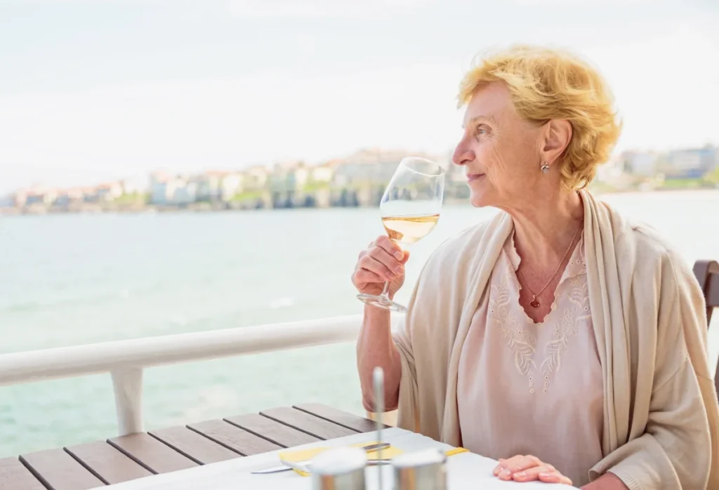 Senior woman enjoying wine on a cafe terrace by the water