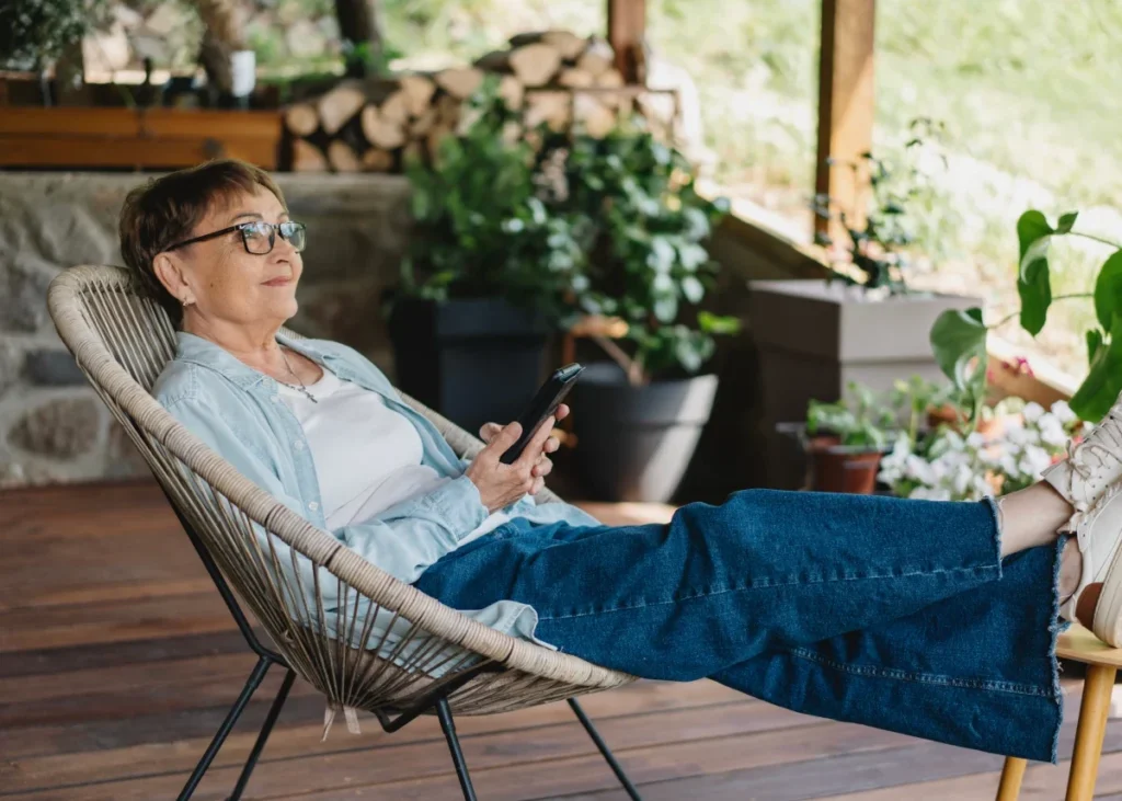Senior woman smiling while looking at her smartphone on a terrace