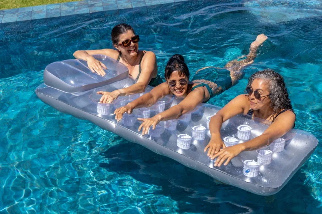 Three smiling women relaxing on an inflatable float in a swimming pool