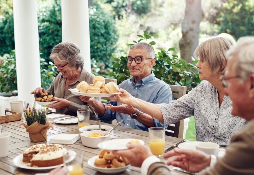 Group of seniors sharing brunch dishes at a table on a covered patio
