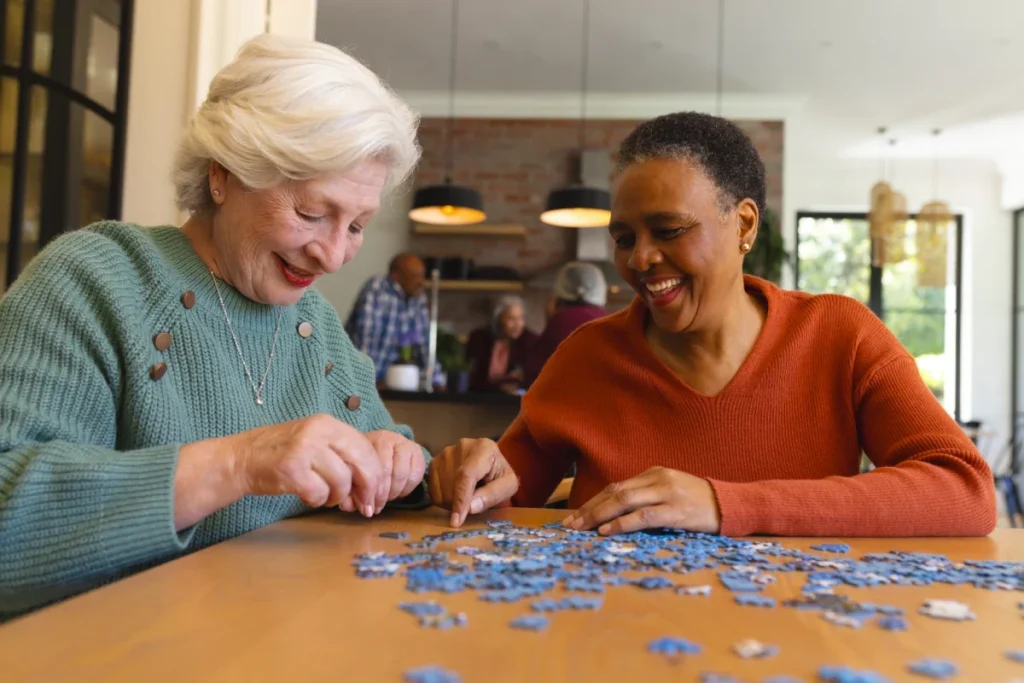 Senior women friends working on a jigsaw puzzle together at home