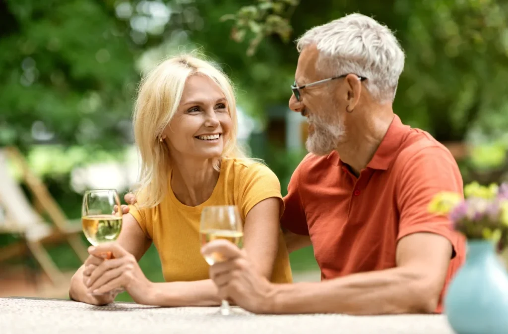 Senior couple smiling and toasting with wine at an outdoor table