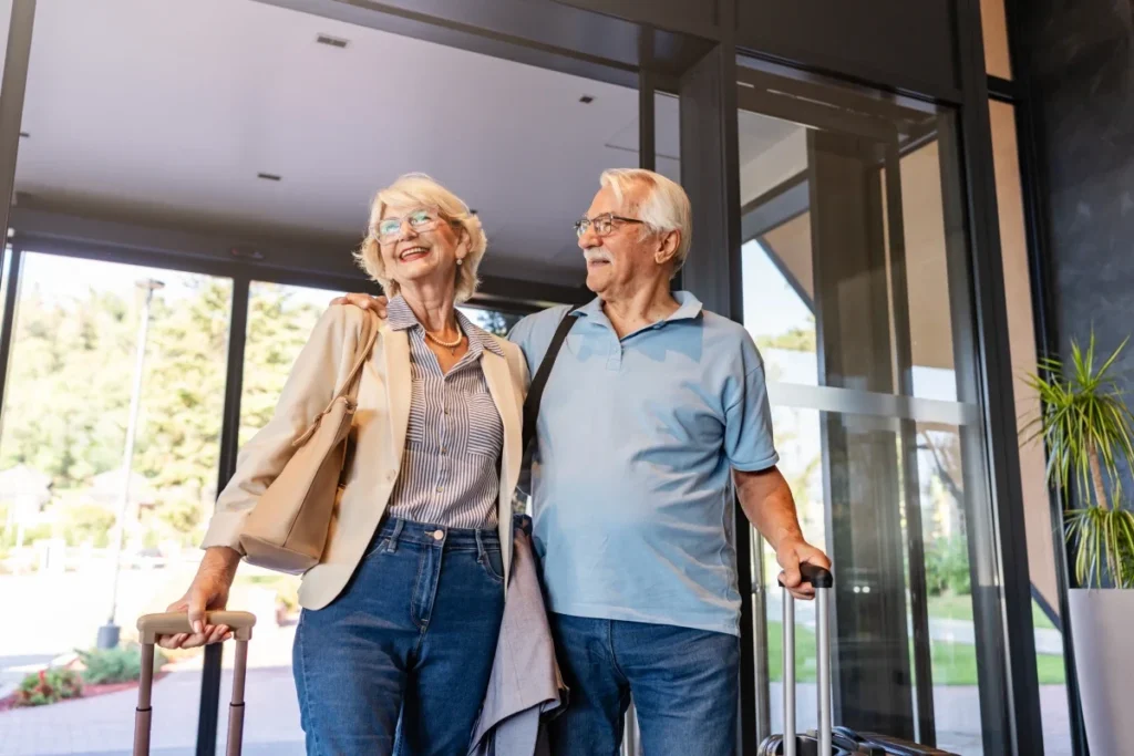 Senior couple entering a hotel lobby with their suitcases, ready for travel