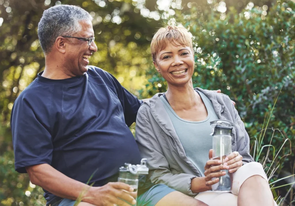 Senior man and woman smiling and relaxing outdoors with water bottles