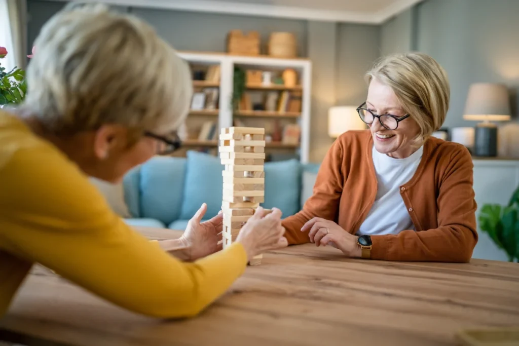 Two senior women friends playing a board game together at home