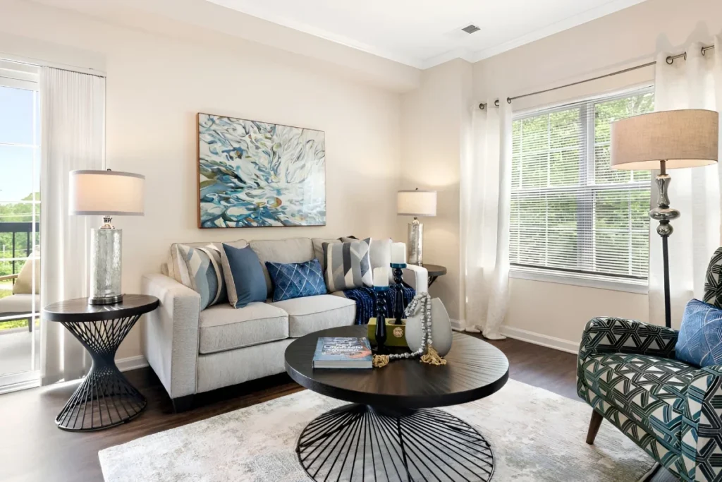 Living room with a gray sofa, blue pillows, a round coffee table and coastal art