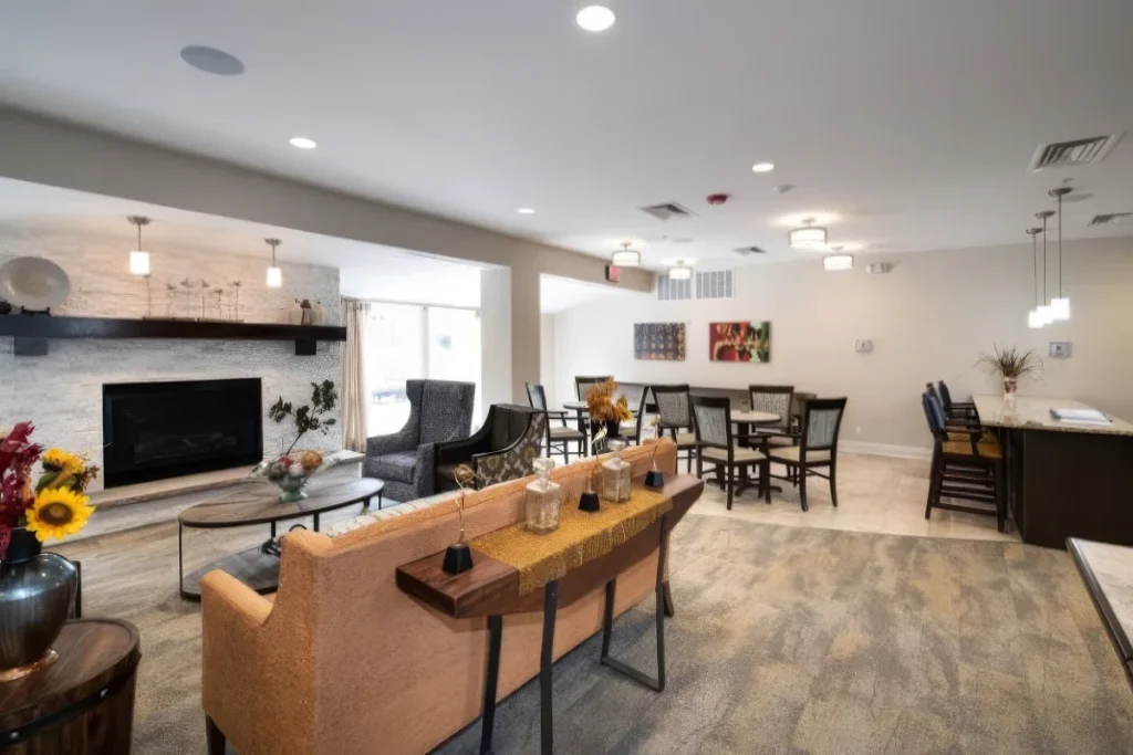 Open living and dining area with a sofa, a fireplace, tables and chairs and a kitchen beyond