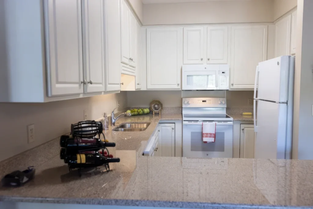 Kitchen with white cabinets, granite counters, a white refrigerator and a microwave