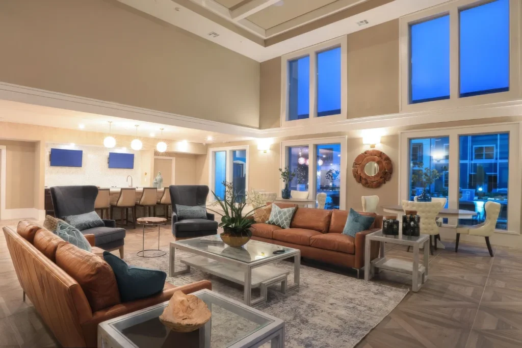 Open lounge with leather sofas and armchairs, tall windows and a coffered ceiling
