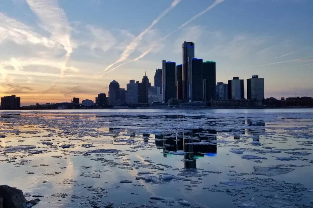 Detroit, Michigan skyline reflected in a frozen, icy waterfront at sunset