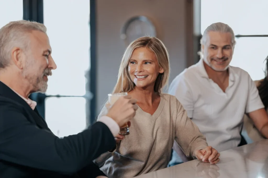 Smiling adults toasting with glasses of wine around a table