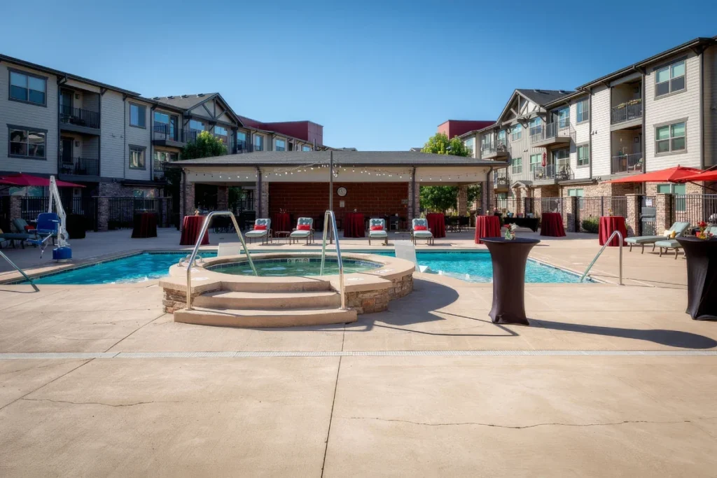 Courtyard pool and hot tub with patio seating, surrounded by multi-story apartment buildings