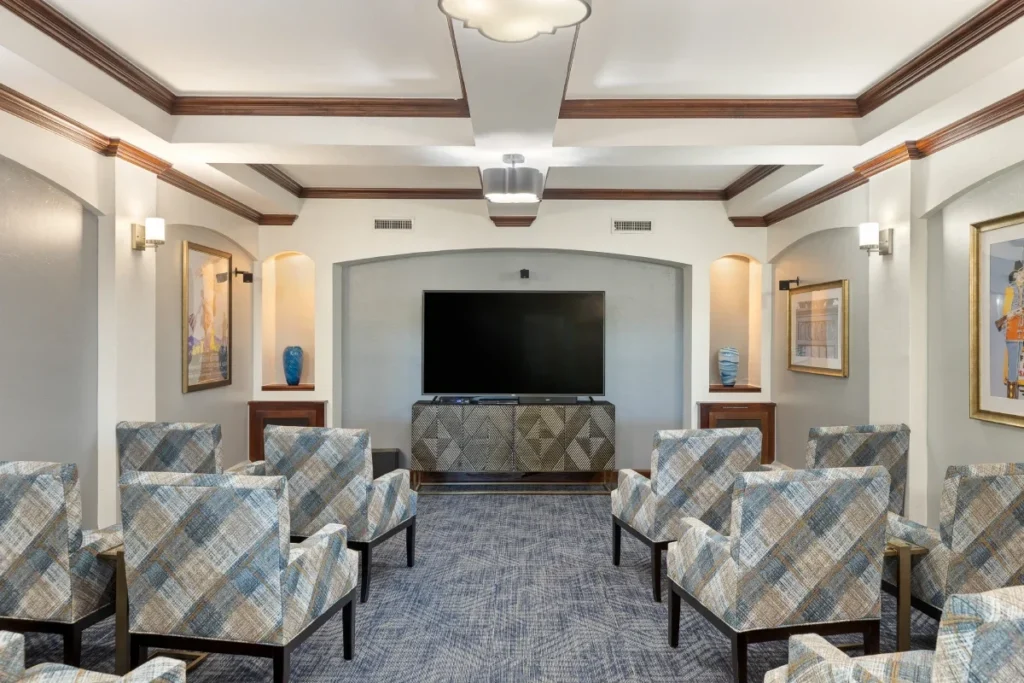 Lounge with plaid armchairs facing a wall-mounted TV, under a coffered ceiling